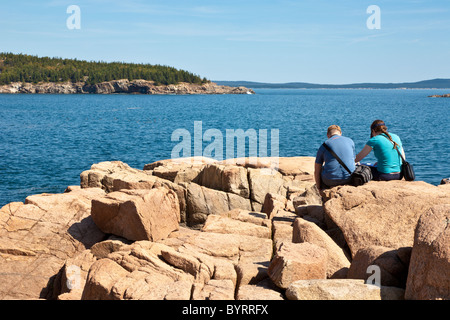 Couple assis sur la côte rocheuse à Thunder Hole dans l'Acadia National Park près de Bar Harbor, Maine Banque D'Images