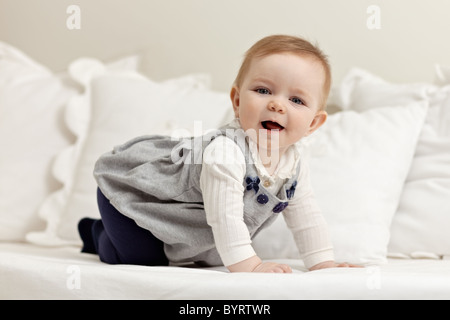 Portrait de 6 mois femme enfant jouant sur le lit et en regardant la caméra. Vue de côté, de forme horizontale, pleine longueur Banque D'Images