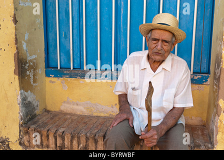 Vieil homme avec un bâton de marche sont assis dans la rue, Trinidad, Sancti Spiritus, Cuba, Caraïbes Banque D'Images