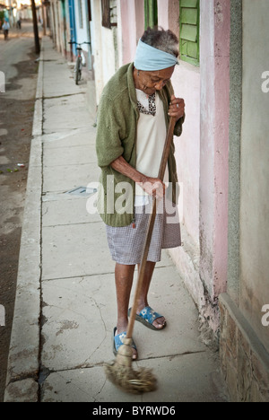 Vieille Femme balayant la rue devant sa maison, Trinidad, Sancti Spiritus, Cuba, Caraïbes. Banque D'Images