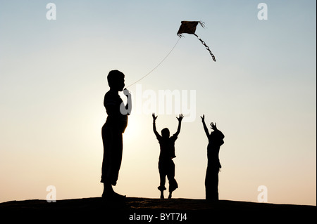 Les jeunes garçons indiens s'amusant voler un cerf-volant de papier fait main dans la campagne indienne. Silhouette Banque D'Images