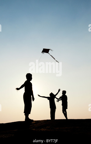 Les jeunes garçons indiens s'amusant voler un cerf-volant de papier fait main dans la campagne indienne. Silhouette Banque D'Images