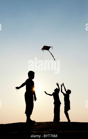 Les jeunes garçons indiens s'amusant voler un cerf-volant de papier fait main dans la campagne indienne. Silhouette Banque D'Images