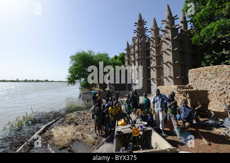 Rassemblement des villageois autour de la proue d'une pinasse en face d'une belle mosquée construite de boue. Mali Banque D'Images