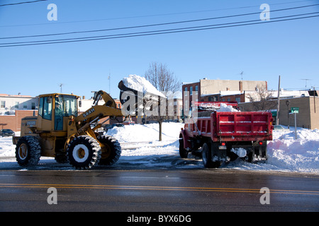Chargeur frontal et Dump Truck déblayer la neige à partir de la rue après la récente tempête de Owosso dans le Michigan USA Banque D'Images