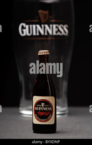 Une bouteille de Guinness miniature en face d'une pinte de Guinness en verre. Banque D'Images