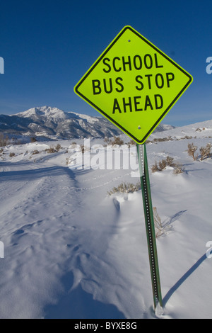 Arrêt de bus scolaire à venir ouvrir une journée d'hiver enneigée dans les Montagnes Rocheuses du Montana USA Banque D'Images