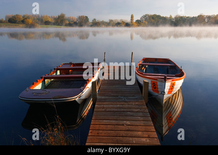 L'aube d'un matin d'automne au lac Mallard dans le Cotswold Water Park. Deux barques sont amarrés à côté d'une jetée Banque D'Images