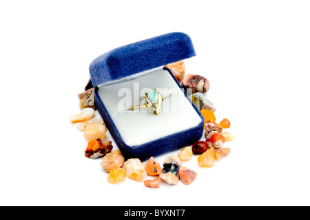 Opal et anneau d'or au cadre bleu sur blanc entouré de pierres brutes Banque D'Images