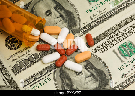 Une variété de pilules et vitamines d'un déversement sur bouteille orange de 100 dollars américains. Banque D'Images