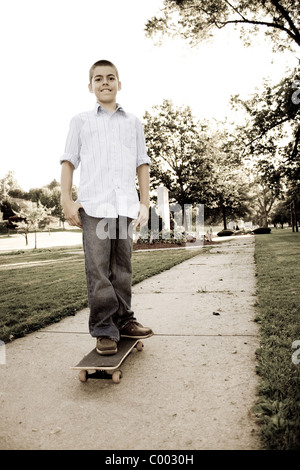 Un jeune adolescent debout sur sa planche à roulettes dans le parc. Sépia. Banque D'Images