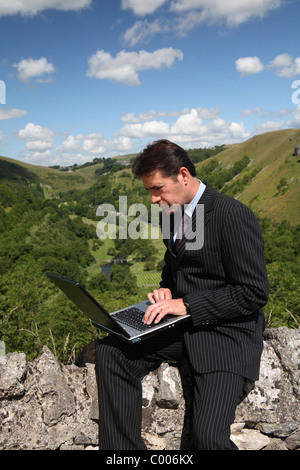 L'homme d'affaires travaillant à l'extérieur avec le haut débit mobile et ordinateur portable Banque D'Images