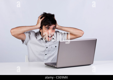 Jeune homme choqué avec quelque chose qu'il voit sur son ordinateur portable Banque D'Images