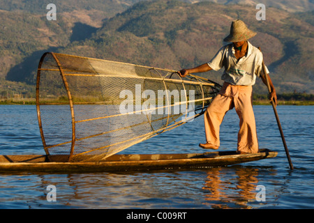 Ethnie Intha leg-pêcheur d'aviron avec panier net sur le lac Inle, Myanmar (Birmanie) Banque D'Images