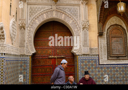 Les hommes à l'entrée de la Mosquée Sidi Ahmed Tijani orné de sculpture sur pierre et carrelage à Fes el Bali Medina Fès Maroc Afrique du Nord Banque D'Images