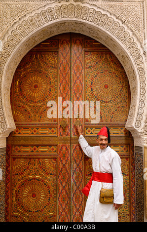 L'homme en robe blanche et rouge et à la porte d'une mosquée avec de la sculpture sur pierre et peinture à Fes el Bali Medina Fès Maroc Afrique du Nord Banque D'Images