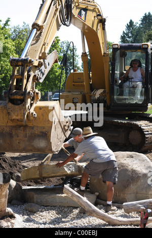 Assurances avec une pelleteuse de placer une pierre dans un étang de la qualité de l'eau paysage décoré Banque D'Images