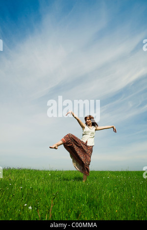 Jeune femme faisant danser pose sur une verte prairie Banque D'Images