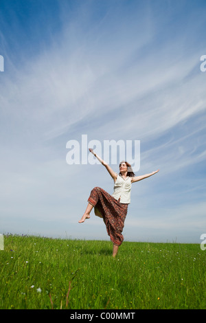 Jeune femme faisant danser pose sur une verte prairie Banque D'Images