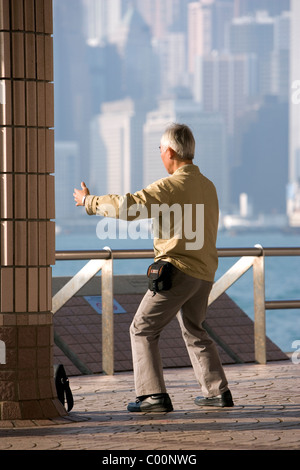 La Chine, Hong Kong, tôt le matin en ville avec l'homme de faire des exercices de Tai Chi avant travaux Banque D'Images