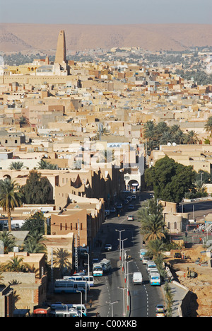 L'Algérie, Ghardaïa, vue de la ville avec des véhicules sur route, habitation en pisé et grand minaret contre ciel clair Banque D'Images