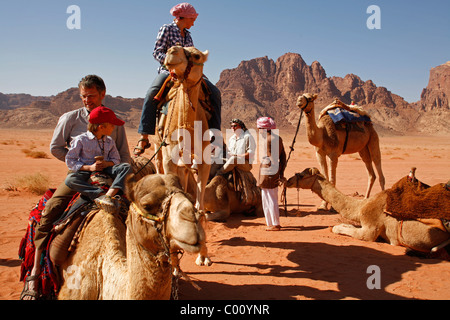 Les touristes chameaux dans le désert, Wadi Rum, Jordanie. Banque D'Images