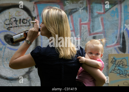 Jeune femme tenant une cigarette et l'alcool hors d'une bouteille de bière, petite fille, 2 ans Banque D'Images