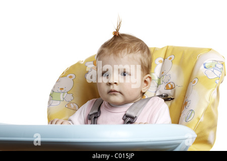 Baby Girl avec des tournants assis sur la chaise haute. Banque D'Images