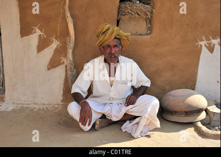 Un homme âgé portant un turban assis en face du mur peint de sa maison, désert de Thar, Rajasthan, Inde, Asie Banque D'Images