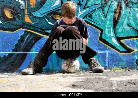 Dix-année-vieux garçon jouant avec sa Nintendo en face d'un mur de graffiti, Germany, Europe Banque D'Images