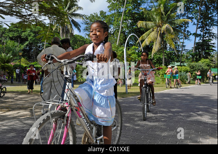 Filles teint foncé sur les bicyclettes dans les rues de La Passe, La Digue, Seychelles Banque D'Images