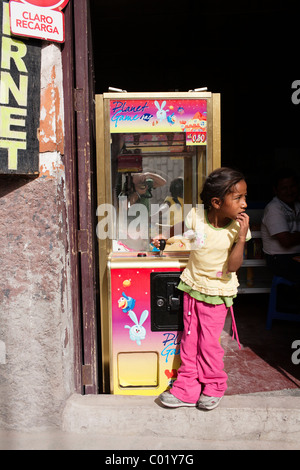 Une jeune fille joue avec un distributeur machine de jeu dans une rue d'Ayacucho Banque D'Images