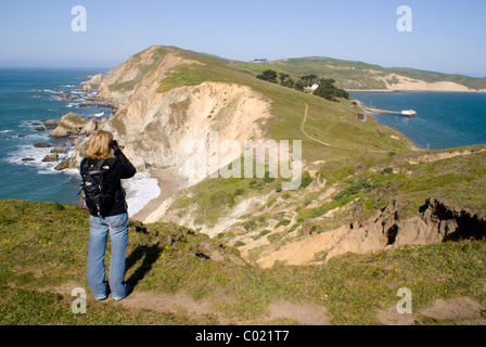 Une femme prend des photos en randonnant sur le sentier pittoresque de Chimney Rock, surplombant les falaises côtières de Point Reyes National Seashore, en Californie. Banque D'Images