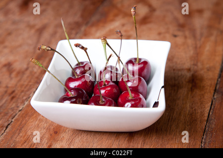 Les cerises dans un bol sur la table en bois Banque D'Images