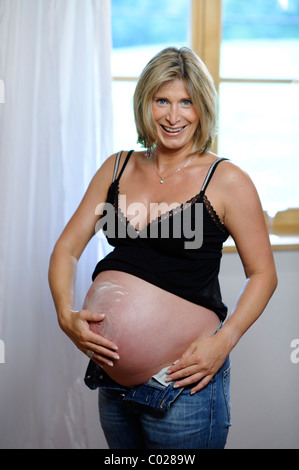 Femme enceinte l'application de lotion sur son ventre Banque D'Images