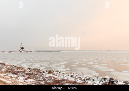 Dutch paysage d'hiver avec la mer gelée et le phare Banque D'Images