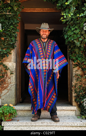 L'homme à long poncho bolivien et hat devant une porte, Tauchersreuth, Middle Franconia, Bavaria, Germany, Europe Banque D'Images