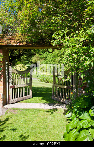 Ouvrir une porte de jardin en bois dans un jardin de campagne anglaise montrant une vue de l'ensemble de jardin au-delà. Banque D'Images