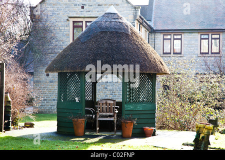 Maison de chaume dans un jardin de ville Banque D'Images