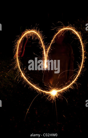 Un coeur en forme de coeur tracé dans les airs par un feu d'artifice étincelant Banque D'Images