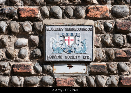 Un signe fort pour la collecte et 'Blakeney Neighbourhood Housing Society Ltd' sur le mur d'un chalet en Blakeney, Norfolk. Banque D'Images