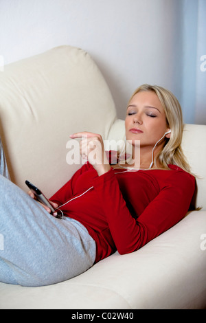 Femme sur le canapé avec mp3 player Banque D'Images