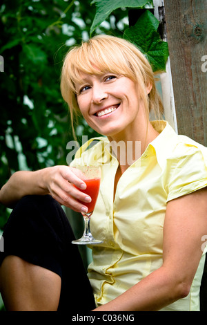 Femme tenant un verre dans le jardin Banque D'Images