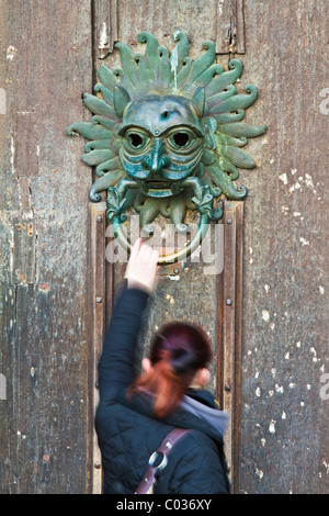 Une femme ayant atteint jusqu'à la réplique du sanctuaire de bronze knocker sur la porte de la cathédrale de Durham, County Durham, Angleterre Banque D'Images