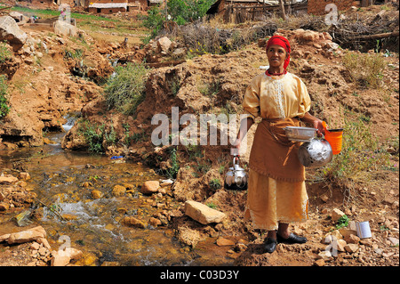 Personnes âgées femme berbère lave sa vaisselle dans un ruisseau, Moyen Atlas, Maroc, Afrique Banque D'Images