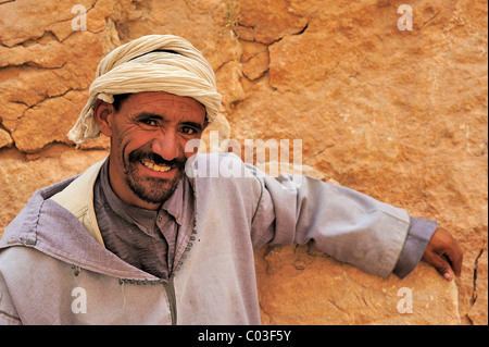 Portrait d'un homme portant un turban et djellaba traditionnelle appuyée contre une paroi de rochers, Gorges de Todra, le Maroc, l'Afrique Banque D'Images