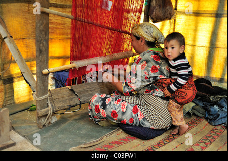 Femme berbère travaillant avec un enfant dans une écharpe sur son métier, Moyen Atlas, Maroc, Afrique Banque D'Images