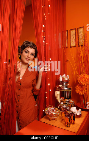 Portrait d'une belle femme peeking through rideaux orange Banque D'Images