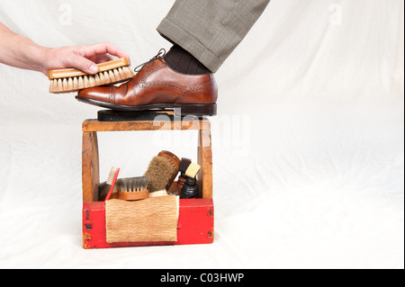 Un homme obtient ses chaussures cirées par un travailleur à l'aide d'une boîte de cirage vintage Banque D'Images