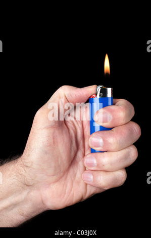 Image d'une personne d'allumer un briquet au butane portable bleu sur un fond noir. Banque D'Images